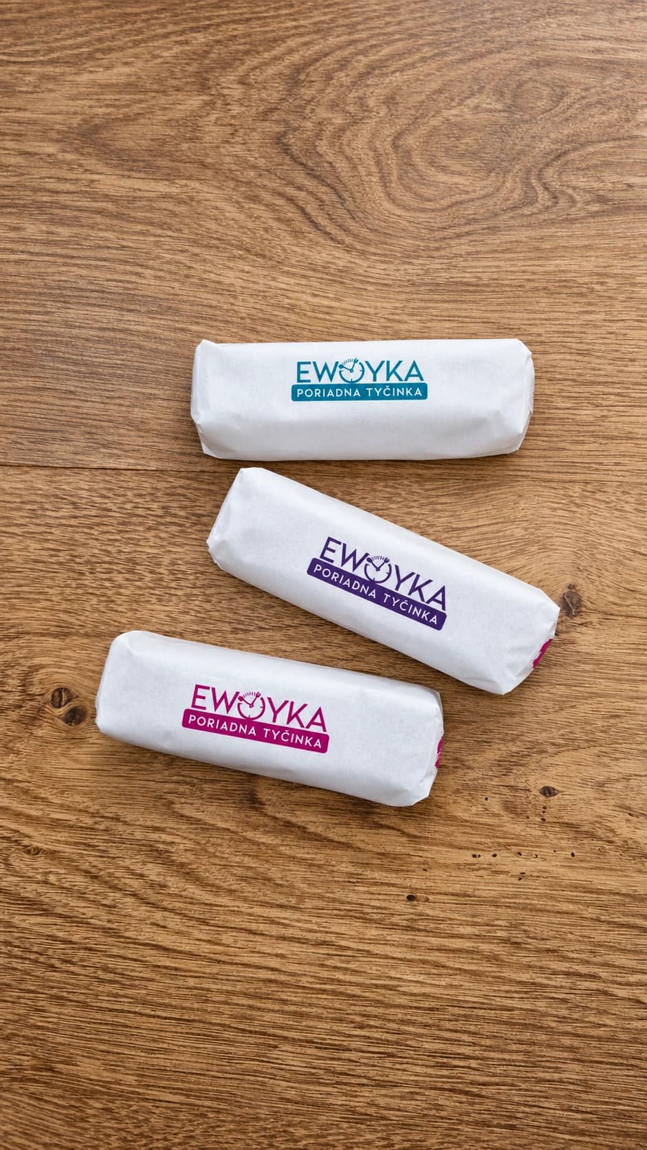 Tri tyčinky EWOYKA v bielych obaloch na drevenom stole